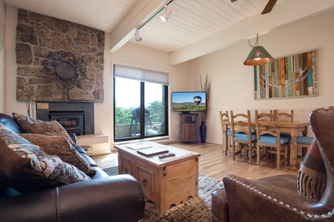Cozy up by your stone fireplace in this rustic-chic living space with exposed beams and warm wood accents.