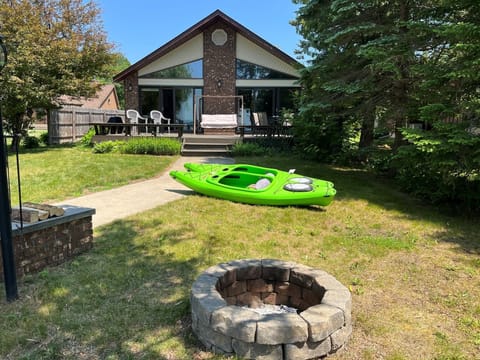Front of house with firepit, kayaks, and large deck
