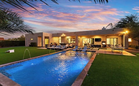 Backyard oasis glowing with pool and water features on warm summer nights.