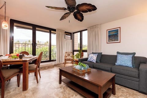 Bright and airy living space featuring a comfortable sleeper sofa, tropical décor, and floor-to-ceiling windows offering mountain views