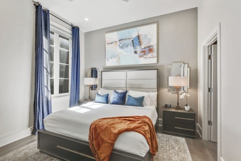 Spacious guest bedroom with king-size bed, ensuite bathroom, and designer closet. Equipped with nightstands, lamps, hangers, luggage rack, alarm clock, white noise machine, and a 50" Samsung Smart 4K TV with streaming apps and DIRECTV Entertainment.