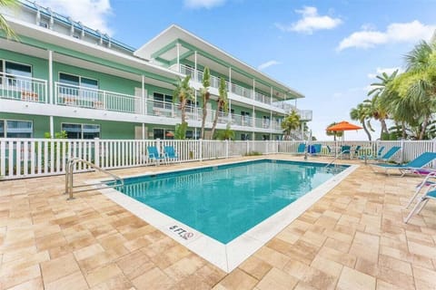 Dive into our sparkling saltwater pool with a spacious sun deck, lounge chairs, and handicap access — all surrounded by swaying palms, steps from the beach.
