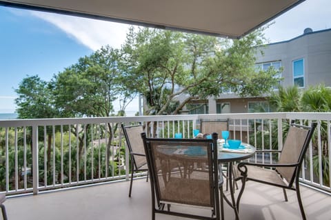 Enjoy elevated coastal views overlooking a beautifully landscaped oceanfront setting, where lush green lawns, mature live oaks, and a tranquil lagoon surround the community pool and sundeck