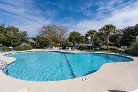 The community pool offers a resort-style setting surrounded by lush trees and open skies—perfect for cooling off after a day at the beach.