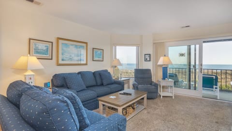 This bright, coastal-inspired living room offers a welcoming space to relax with comfortable seating, tile flooring, and soft seaside décor.