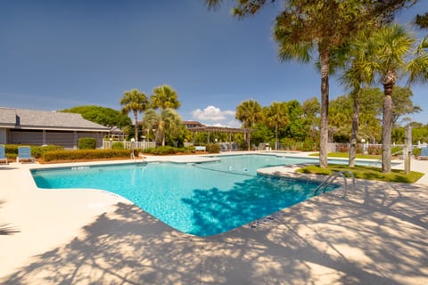 The community pool area offers a refreshing coastal retreat surrounded by lush landscaping and swaying palms.