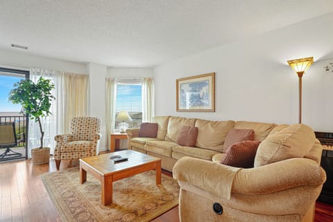 Gather in the inviting living room after a day on the beach, featuring comfortable seating, warm hardwood flooring, and abundant natural light.