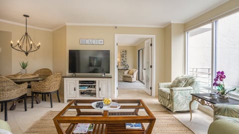 The seating is arranged for easy conversation and movie nights, with a flat-screen TV and soft coastal furnishings throughout.