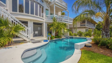This private backyard oasis showcases a stunning resort-style pool surrounded by lush tropical landscaping.