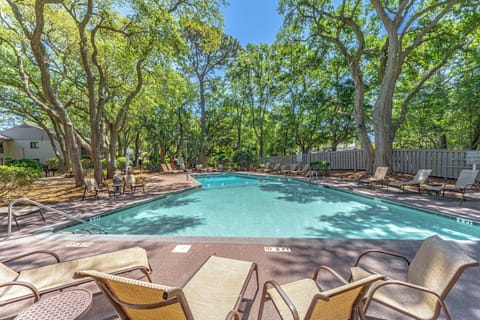 Surrounded by towering live oaks, palmettos, and mature landscaping, the pool area offers a peaceful setting.