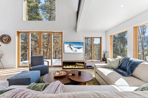 Sink into plush seating by the modern fireplace while natural light floods through floor-to-ceiling windows, creating your perfect mountain retreat sanctuary.