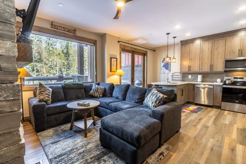 Relax on your spacious sectional sofa while enjoying mountain views through large windows in this modern, open-concept living space.