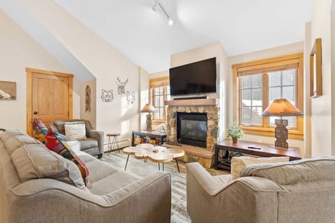 Curl up by your crackling stone fireplace in this cozy living room, where warm wood accents and plush seating create the perfect mountain retreat.