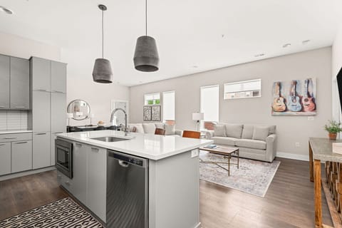Modern open-concept kitchen and living area featuring sleek cabinetry, quartz countertops, stainless steel appliances, and abundant natural light.