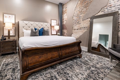 Spacious primary bedroom with a king-size bed, ensuite bathroom, and built-in closets. Includes nightstands, lamps, hangers, luggage racks, an alarm clock, a white noise machine, and a 50" Samsung Smart 4K TV for streaming and DIRECTV Entertainment.