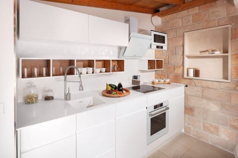 The white, modern and tall kitchen of the luxury villa Zlatni Rat in Bol on the island of Brač and the living area with a dining table with served breakfast