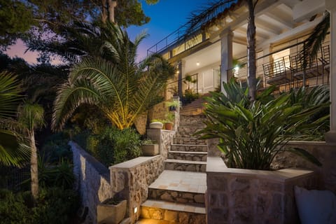 A garden decorated with greenery and palm trees and stairs leading to the outdoor terrace of Croatia luxury villa for rent Anemos on the island of Hvar