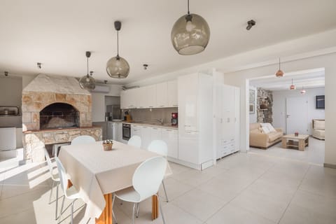 The interior of Croatia luxury villa by the Anemos beach with a dining table, a kitchen equipped with an oven, a stove, a coffee machine and an indoor fireplace.