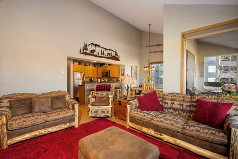 Unwind in your cozy living room with mountain-themed décor, plush seating, and an open kitchen perfect for preparing meals together.