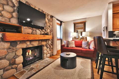 Living room features a gas burning fireplace with rock surround and large flat screen TV