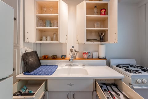 Kitchen stocked up with glassware, oven and stove top and fridge.