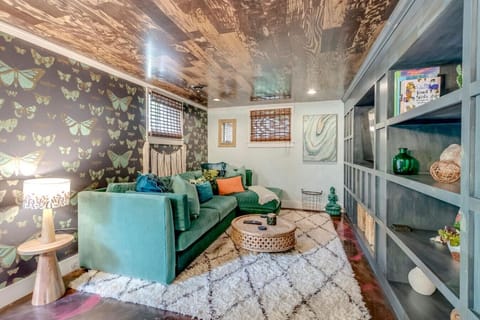 A lush butterfly wallpaper, teal couch, and warm bohemian accents make the living room a true showstopper.