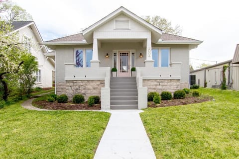Exterior front of craftsman-style home with stone facade, green lawn, and front steps