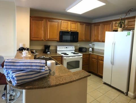 Full size refrigerator along with stocked cabinets with pot, dishes & cutlery