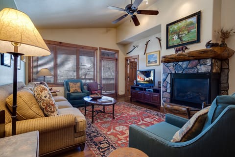 Unwind in your cozy living space with rustic stone fireplace, plush seating, and warm mountain lodge ambiance.