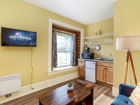 Living space with love seat, lift-top coffee table, Smart TV and kitchenette.