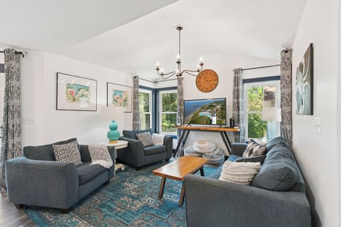 Picture yourself unwinding on plush sofas surrounded by natural light and charming décor. The cozy living room invites relaxation with soft throws, artwork, and a vibrant rug underfoot.