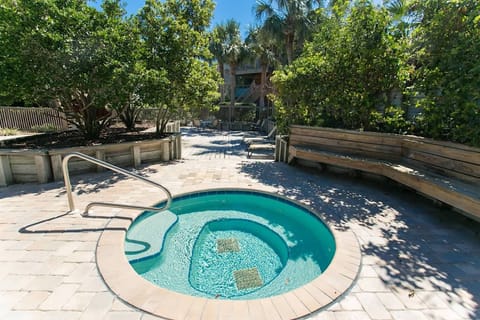 Private hot tub with curved seating surrounded by trees and built in benches.