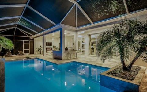 Heated pool inside the screened lanai enclosure with views into the indoor living space beyond