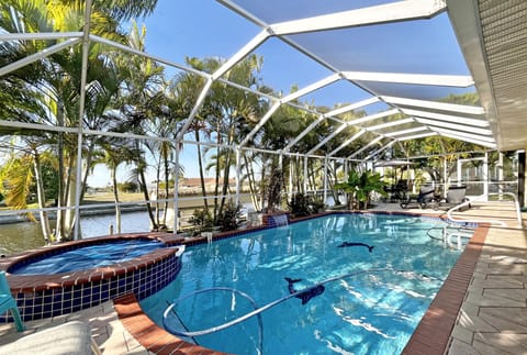 Screened heated pool and spa with paver deck and wide canal views