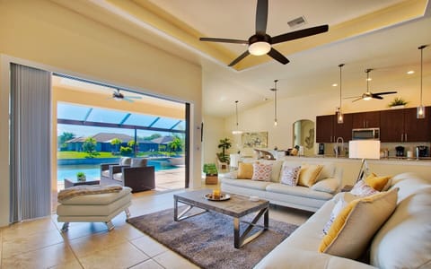 Open living area with sectional sofa and sliding glass doors fully open to the pool and backyard