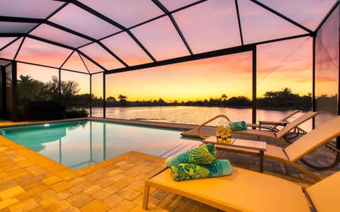 Heated pool with lounge chairs and tropical landscaping bathed in sunset light