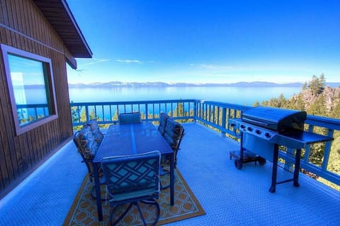 Deck with large lake view, pine trees, mountains, and deck.