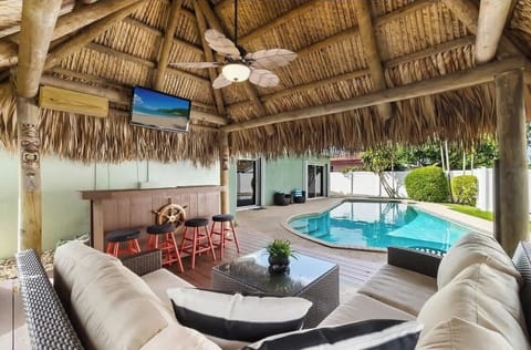 Tropical tiki with outdoor bar, tv, and lounge area overlooking amazing pool