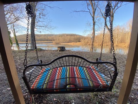 Porch swing below facing river with fire pit 