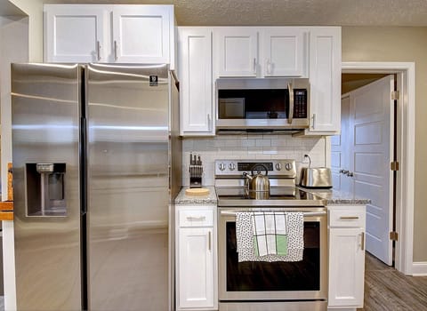Fridge and oven in the kitchen with backsplash.