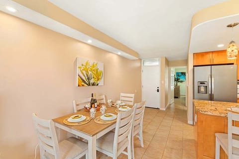 Dine in style with a set table and floral artwork, just steps from a modern kitchen with stainless steel appliances.