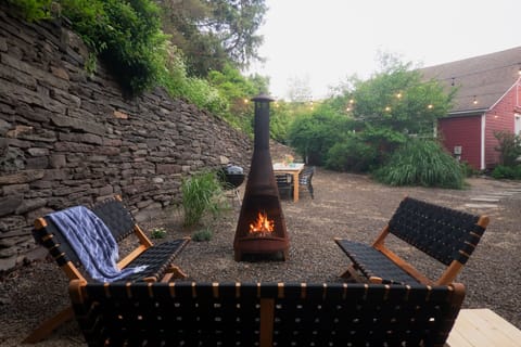 Pea gravel patio with chiminea, grills, and dining area with sun umbrellas. 