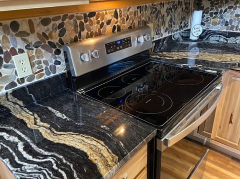 Beautiful exotic granite with stone back splash lend sophistication to this rustic cabin.