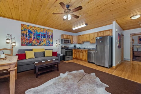 Step into your cozy mountain retreat with warm wood ceilings, a comfortable living space, and a fully equipped kitchen ready for your stay. The vibrant artwork and rustic touches create a welcoming atmosphere you'll love coming home to.