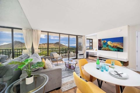Modern living room with floor-to-ceiling windows offering mountain views and a balcony seating area.