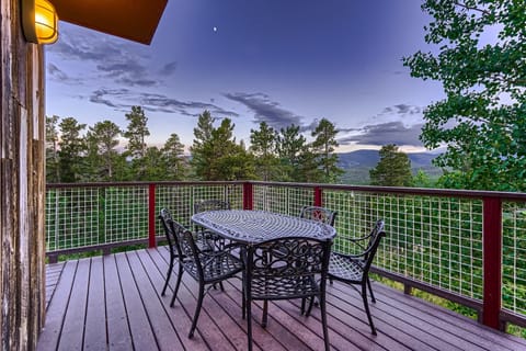 A deck with a table and chairs overlooking the mountains.