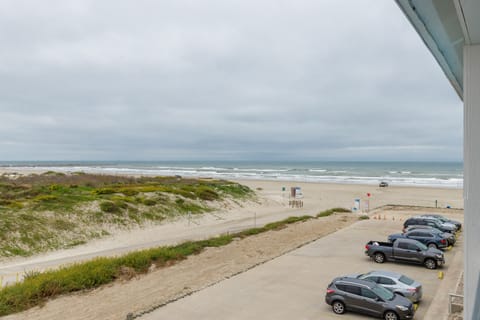 Expansive oceanfront view showcasing pristine beach access and convenient parking facilities directly adjacent to sandy shores and rolling waves.