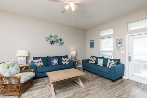 Sink into plush navy sofas in your coastal-themed living room, where ocean breezes flow through bright windows and nautical touches create seaside serenity.