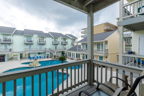 Relax on your private balcony overlooking the sparkling pool courtyard, where colorful beach houses create a charming coastal community atmosphere.