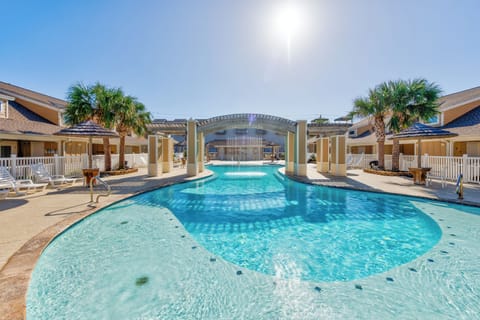 Resort-style pool with crystal clear waters surrounded by palm-lined vacation rentals under bright Florida sunshine.